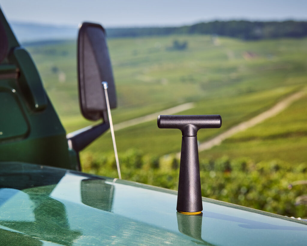 Le Vigneron - Black posé sur un 4x4 devant un paysage de vigne